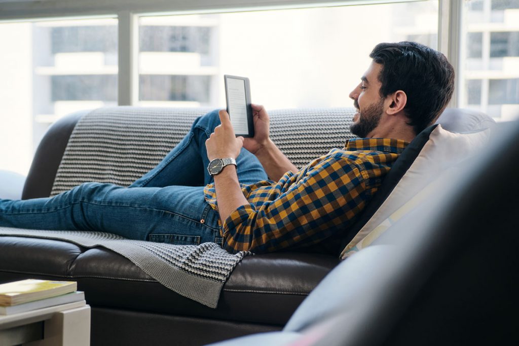 Uomo che legge un ebook sul divano in salotto